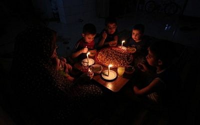 Une famille palestinienne mange son dîner avec des bougies dans leur maison improvisée au camp de réfugiés de Rafah, dans le sud de la bande de Gaza, lors d'une coupure d'électricité, le 11 juin 2017. (AFP/Said Khatib)
