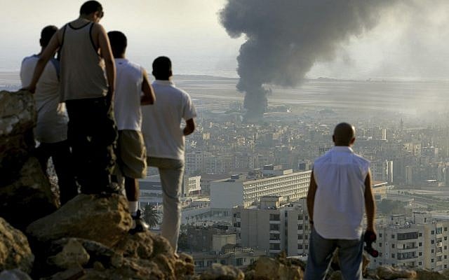 Sur cette photo datée du 14 juillet 206, des jeunes libanais sont rassemblés sur une colline surplombant la ville de Beyrouth au Liban au coucher du soleil afin d'observer la fumée qui s'échappe d'un réservoir de carburant à l'aéroport international de Beyrouth, qui a été touché par une frappe israélienne. (Crédit : Ben Curtis/AP) Sur cette photo datée du 14 juillet 206, des jeunes libanais sont rassemblés sur une colline surplombant la ville de Beyrouth au Liban au coucher du soleil afin d'observer la fumée qui s'échappe d'un réservoir de carburant à l'aéroport international de Beyrouth, qui a été touché par une frappe israélienne. (Crédit : Ben Curtis/AP)