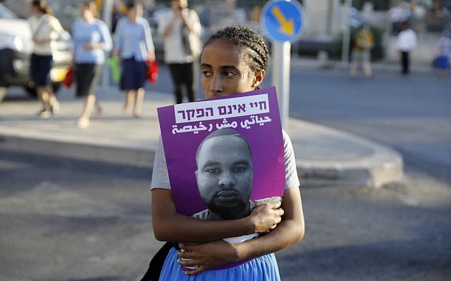 Une Israélienne tient une affiche à l'effigie de Solomon Tekah, un Israélien d'origine éthiopienne tué par un policier, pendant des manifestations dénonçant le racisme dont cette minorité fait l'objet, le 2 juillet 2019. (Crédit : MENAHEM KAHANA / AFP) Une Israélienne tient une affiche à l'effigie de Solomon Tekah, un Israélien d'origine éthiopienne tué par un policier, pendant des manifestations dénonçant le racisme dont cette minorité fait l'objet, le 2 juillet 2019. (Crédit : MENAHEM KAHANA / AFP)