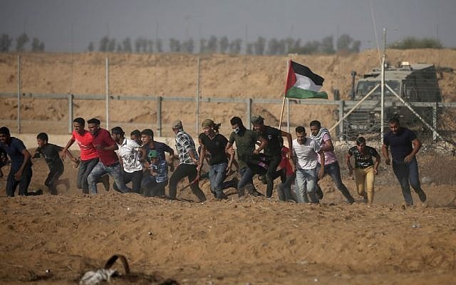 Des manifestants palestiniens fuient la clôture pendant les manifestations le long de la frontière avec Israël, à l'est de Khan Younis, dans le sud de Gaza, le 12 juillet 2019 (Crédit : Mahmud Hams/AFP) Des manifestants palestiniens fuient la clôture pendant les manifestations le long de la frontière avec Israël, à l'est de Khan Younis, dans le sud de Gaza, le 12 juillet 2019 (Crédit : Mahmud Hams/AFP)
