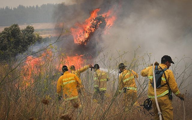 Des pompiers tentent d'éteindre un incendie de broussailles près du Moshav Aderet, le 17 juillet 2019. (Noam Revkin Fenton/Flash90)