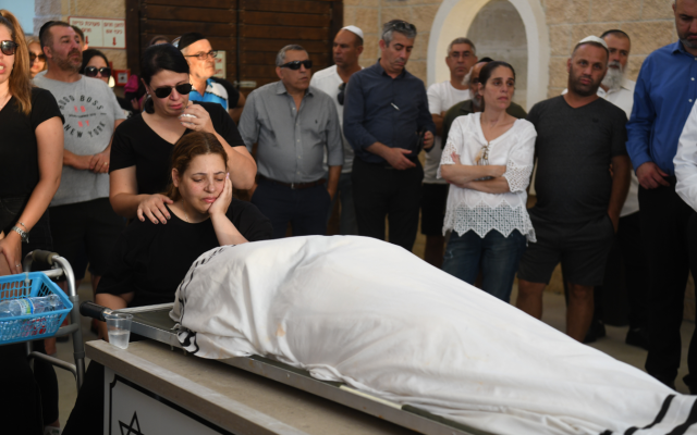 Dikla Hasdai se recueille près du corps de son mari, Ofir Hasdai qui a été abattu dans un parking de Ramle, lors de ses funérailles au cimetière de Ramle, le 29 juillet 2019. (Avi Dishi/Flash90) Dikla Hasdai se recueille près du corps de son mari, Ofir Hasdai qui a été abattu dans un parking de Ramle, lors de ses funérailles au cimetière de Ramle, le 29 juillet 2019. (Avi Dishi/Flash90)