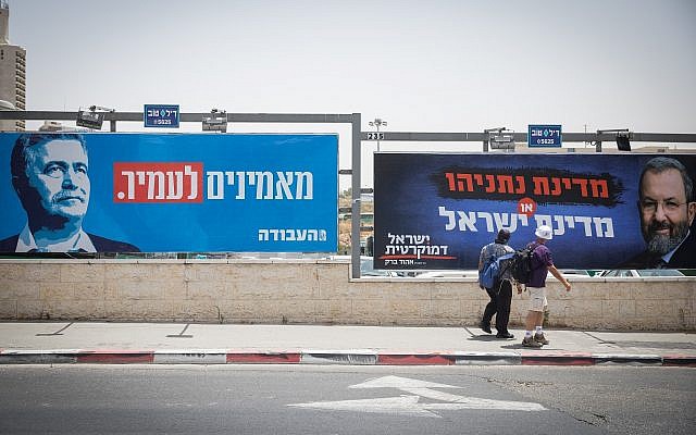 Des gens marchent devant des affiches de la campagne électorale montrant les chef du parti Travailliste Amir Peretz, à gauche, et Ehud Barack, à droite, à l'entrée de Jérusalem, le 17 juillet 2019. (Noam Revkin Fenton/Flash90) Des gens marchent devant des affiches de la campagne électorale montrant les chef du parti Travailliste Amir Peretz, à gauche, et Ehud Barack, à droite, à l'entrée de Jérusalem, le 17 juillet 2019. (Noam Revkin Fenton/Flash90)