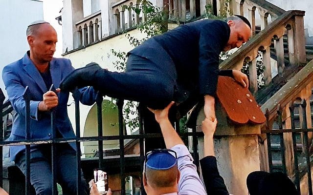 Le grand rabbin polonais Michael Schudrich grimpe sur la clôture d'une synagogue barricadée (Crédit : Shimon Briman/JTA) Le grand rabbin polonais Michael Schudrich grimpe sur la clôture d'une synagogue barricadée (Crédit : Shimon Briman/JTA)