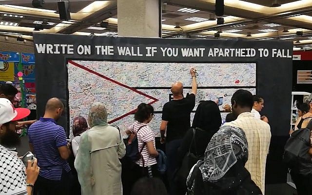 Des participants à la Palestine Expo 2017 à Lodnres écrivent sur un mur pour dénoncer "l'apartheid" israélien. Crédit : capture écran/YouTube)