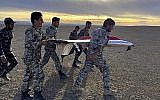 Sur cette photo fournie par l'armée iranienne, des soldats transportent les débris d'un drone durant des exercices à Semnan, en Iran (Crédit : Armée iranienne via AP)