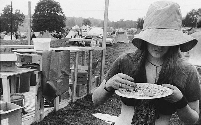 Une jeune femme se sert une ration gratuite dans le camp du festival de musique de Woodstock de Bethel, à New York, le 15 août 1969 (Crédit : AP Photo)