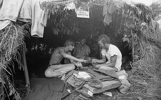Des fans de musique sous une hutte en herbe au festival d'art et de musique de Woodstock, le 17 août 1969 (Crédit : AP Photo)