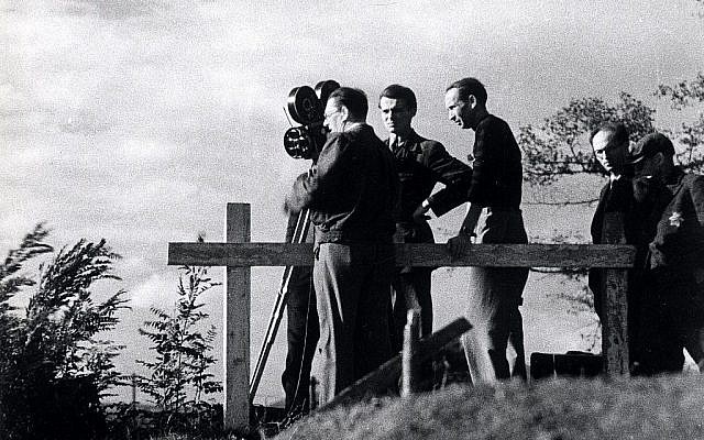 Une équipe de tournage réalise des prises de vue dans le ghetto de Theresienstadt lors du tournage d'un film de propagande nazie en 1944. Un assistant juif portant une étoile de David est à droite. (Domaine public)