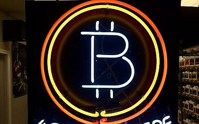 Sur cette photo du 7 février 2018, on peut voir un signe en néon suspendu à la vitrine de la boutique Healthy Harvest Indoor Gardening à Hillsboro, dans l'Oregon. Cela montre que l'entreprise accepte le bitcoin comme moyen de paiement. (AP Photo/Gillian Flaccus, File)