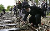 Dans cette photo du 9 mai 2015, un homme pose une rose sur un rail de chemin de fer à l'ancien camp de concentration de Westerbork, aux Pays-Bas, se souvenant que 100 000 Juifs ont été transportés depuis Westerbork vers un camp de la mort nazi. (AP Photo/Peter Dejong)