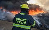 Un pompier travailler à éteindre un incendie causé par un engin explosif lancé depuis la bande de Gaza vers le sud d'Israël, le 27 juin 2019. (Crédit : pompiers israéliens)