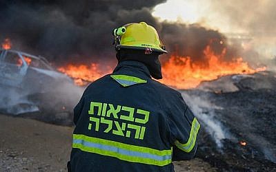 Un pompier travailler à éteindre un incendie causé par un engin explosif lancé depuis la bande de Gaza vers le sud d'Israël, le 27 juin 2019. (Crédit : pompiers israéliens)