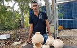 Ahmed Nassar Yassin avec les artéfacts vieux de 4500 ans qu'il a découverts dans une grotte funéraire près d'Araba, dans le nord d'Israël (Crédit : Nir Distelfeld/Autorité israélienne des antiquités)