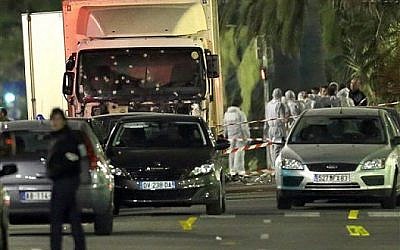 Les experts médico-légaux près d'un camion dont le pare-brise est criblé de balles après un attentat contre la foule venue voir le feu d'artifice lors de la fête nationale dans la ville de Nice, le 15 juillet 2016 (Crédit : AP Photo/Claude Paris)