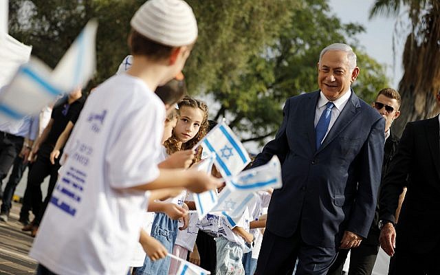 Le Premier ministre Benjamin Netanyahu, à droite, salue les élèves qui brandissent des drapeaux israéliens lors d'une cérémonie organisée lors de la rentrée scolaire dans l'implantation d'Elkana, en Cisjordanie, le 1er septembre (Crédit : Amir Cohen/Pool Photo via AP) Le Premier ministre Benjamin Netanyahu, à droite, salue les élèves qui brandissent des drapeaux israéliens lors d'une cérémonie organisée lors de la rentrée scolaire dans l'implantation d'Elkana, en Cisjordanie, le 1er septembre (Crédit : Amir Cohen/Pool Photo via AP)