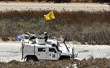 Les forces de maintien de la paix espagnoles de l'ONU patrouillant sur la frontière israélo-libanaise passent devant un drapeau du Hezbollah, dans le village de Kfar Kila, dans le sud du Liban, le 2 septembre 2019 (Crédit :  AP Photo/Hussein Malla)