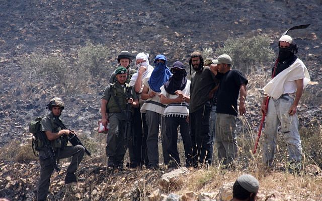 Des résidents de Yitzhar masqués et des soldats surveillent les champs palestiniens incendiés dans le village d'Asira al-Qiblyia le 2 juin 2010. (Wagdi Ashtiyeh/Flash90) Des résidents de Yitzhar masqués et des soldats surveillent les champs palestiniens incendiés dans le village d'Asira al-Qiblyia le 2 juin 2010. (Wagdi Ashtiyeh/Flash90)