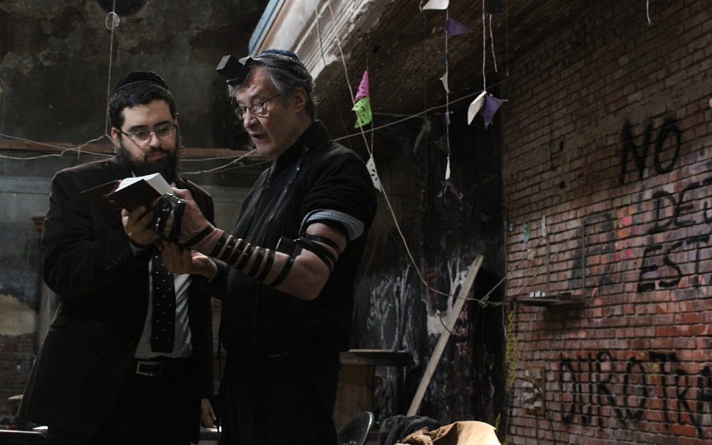 Le rabbin Shneur Mizrahi, à gauche, aide  Ricardo Aisen à prier avec des phylactères dans la synagogue du quartier de La Boca de Buenos Aires, qui vient d'être rendue à la communauté juive (Crédit : Daniel Silicaro)
