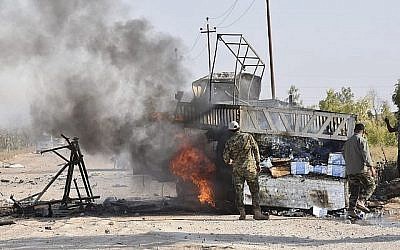 Des membres des Unités de mobilisation populaire se tiennent à côté d'un camion en feu après une attaque de drone imputée à Israël, à proximité du point de passage Qaim, dans la province d'Anbar, en Iraq, le 25 août 2019. (AP Photo)