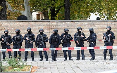 Des policiers se tiennent devant le mur d'un cimetière juif proche du site d'une fusillade à Halle an der Saale, à l'est de l'Allemagne, le 9 octobre 2019. (Crédit : Sebastian Willnow / dpa / AFP / Germany OUT)