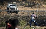 Illustration : Un Palestinien armé d'une fronde fjette des pierres aux forces israéliennes durant une émeute le long de la frontière avec Israël, à l'est de Bureij, dans le centre de la bande de Gaza, le 18 octobre 2019 (Crédit : Mahmud Hams/AFP)