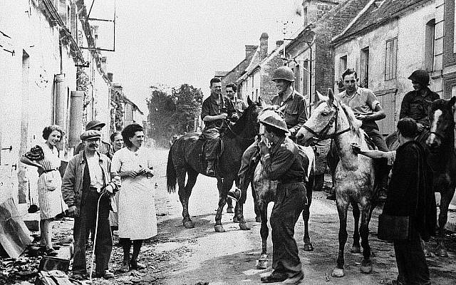 Les soldats américains sur des chevaux capturés aux Allemands battant en retraite rencontrant des habitants lors de leur entrée dans la ville française de Chambois, en Normandie, le 30 août 1944 (Crédit : AP)