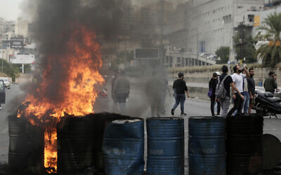 Des manifestants anti-gouvernements incendient des pneus pour bloquer une autoroute qui relie Beyriuth au nord du Liban à Zouk Mosbeh, le 28 octobre 2019. (Crédit : AP Photo/Hassan Ammar)