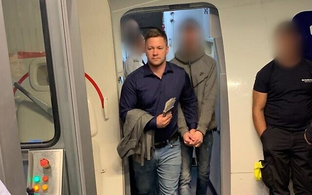 L'un des deux suspects (au centre) d'un meurtre à Petah Tivka, extradé depuis la Russie et arrêté à l'atterrissage en Israël, le 31 octobre 2019. (Crédit : police israélienne) L'un des deux suspects (au centre) d'un meurtre à Petah Tivka, extradé depuis la Russie et arrêté à l'atterrissage en Israël, le 31 octobre 2019. (Crédit : police israélienne)