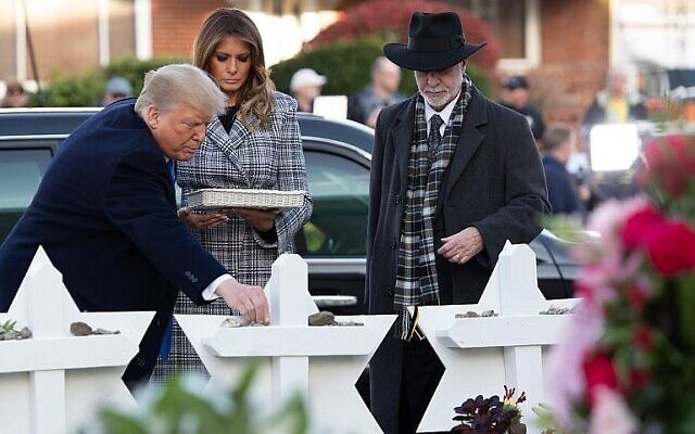 Le président américain Donald Trump et la Première dame Melania Trump, accompagnés par le rabbin Jeffrey Myers, placent des fleurs sur un mémorial en hommage aux victimes de la fusillade survenue à la synagogue Tree of Life de Pittsburgh, en Pennsylvanie, le 30 octobre 2019 (Crédit : Saul Loeb/AFP)