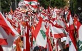 Des partisans du président libanais Michel Aoun agitent des drapeaux nationaux et des bannières de couleur orange du parti politique qu'il a fondé (Le Mouvement patriotique libre) lors d'une contre manifestation à proximité du palais présidentiel à Baabda le 3 novembre 2019.(Photo by Anwar AMRO / AFP)