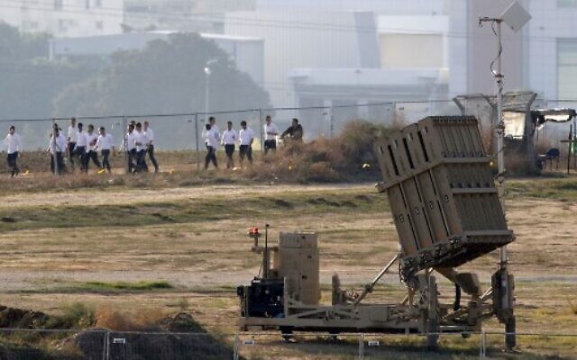 Des étudiants israéliens marchent devant une batterie du système de défense antimissiles du Dôme de fer, chargé d'intercepter et de détruire les roquettes à courte-portée et les obus d'artillerie dans la ville d'Ashdod, dans le sud d'Israël, près de la bande de Gaza, le 12 novembre 2019 (Crédit : JACK GUEZ / AFP) Des étudiants israéliens marchent devant une batterie du système de défense antimissiles du Dôme de fer, chargé d'intercepter et de détruire les roquettes à courte-portée et les obus d'artillerie dans la ville d'Ashdod, dans le sud d'Israël, près de la bande de Gaza, le 12 novembre 2019 (Crédit : JACK GUEZ / AFP)
