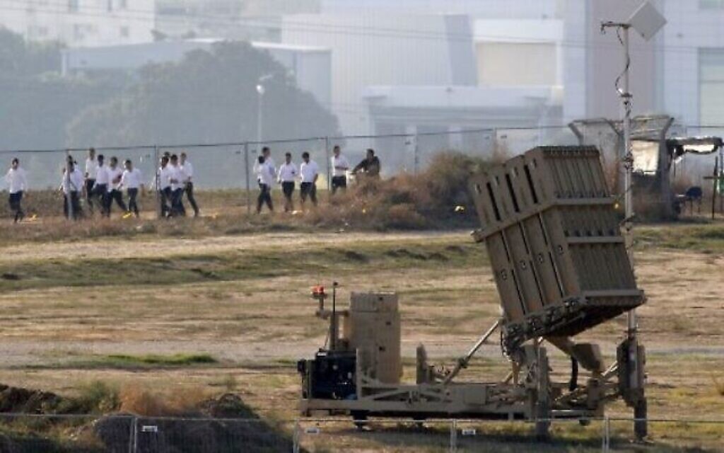 Des étudiants israéliens marchent devant une batterie Dôme de fer, conçu pour intercepter et détruire des roquettes de courte portée et des obus de mortier, Ashdod, le 12 novembre 2019 (Crédit : JACK GUEZ / AFP)