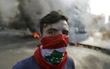 Un manifestant libanais se trouve devant des pneus et des débris en feu dans la zone de Jal el-Dib, dans la banlieue nord de la capitale libanaise de Beyrouth, le 13 novembre 2019.  (Photo par JOSEPH EID / AFP)