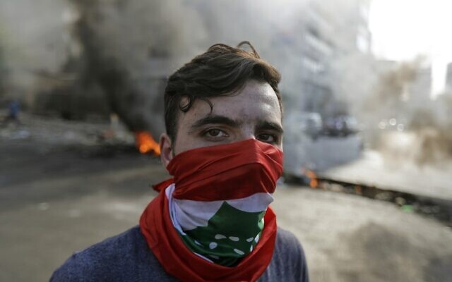 Un manifestant libanais se trouve devant des pneus et des débris en feu dans la zone de Jal el-Dib, dans la banlieue nord de la capitale libanaise de Beyrouth, le 13 novembre 2019.  (Photo par JOSEPH EID / AFP)