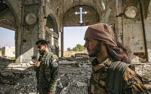 Des membres de la milice syrienne assyrienne des gardes du Khabour (MNK), affiliée aux Forces démocratiques syriennes (FDS), marchent dans les ruines de l'église assyrienne de la Vierge Marie, qui avait été détruite le 15 novembre 2019 dans le village de Tal Nasri, au sud de Tal Tamr (province du Hasakah, au nord-est du pays). (Crédit : Delil souleiman / AFP) Des membres de la milice syrienne assyrienne des gardes du Khabour (MNK), affiliée aux Forces démocratiques syriennes (FDS), marchent dans les ruines de l'église assyrienne de la Vierge Marie, qui avait été détruite le 15 novembre 2019 dans le village de Tal Nasri, au sud de Tal Tamr (province du Hasakah, au nord-est du pays). (Crédit : Delil souleiman / AFP)
