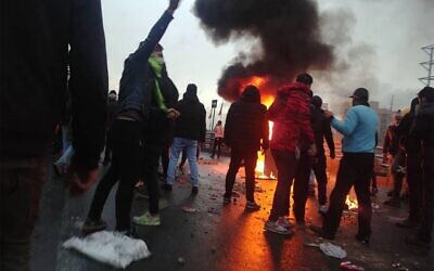Des manifestants iraniens se rassemblent autour d'un feu lors d'une manifestation contre la hausse des prix de l'essence dans la capitale Téhéran, le 16 novembre 2019. (Crédit : AFP)