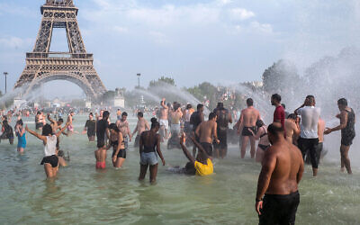 Des Français se rafraîchissent dans les fontaines des jardins du Trocadéro, à Paris, le 25 juillet 2019, pendant un épisode de canicule. (Crédit : AP Photo/Rafael Yaghobzadeh)