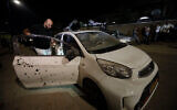 Un homme regarde une voiture endommagée par un éclat d'obus issu d'une roquette tirée de Gaza à Sdérot, en Israël, le 1er novembre 2019 (Crédit : AP Photo/Tsafrir Abayov)