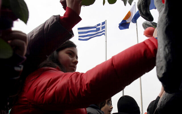 Photo d'illustration : Des enfants mettent des fleurs sur un site de commémoration de la Shoah en souvenir des persécutions des Juifs pendant la Seconde guerre mondiale à Thessalonique, en Grèce, le 27 janvier 2013 (Crédit : AP Photo/Nikolas Giakoumidis)