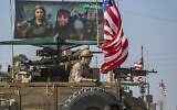 Un véhicule blindé américain passant devant un panneau publicitaire des Unités de protection des femmes kurdes syriennes (YPJ), lors d’une patrouille dans la ville de Qahtaniyah, au nord-est de la Syrie, à la frontière avec la Turquie, le 31 octobre 2019. (Crédit : Delil Souleiman/AFP)