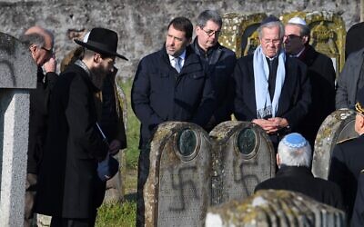 Le ministre français de l'Intérieur, Christophe Castaner (C) et le président du Conseil national des Archives françaises, Jean-Louis Debre (2ndD), visitent le cimetière juif de Westhoffen, le 4 décembre 2019, dans l'est de la France, où 107 tombes ont été découvertes vandalisées avec des croix gammées et des inscriptions antisémites. (Crédit : Patrick HERTZOG / AFP)