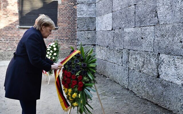 La chancelière allemande Angela Merkel dépose une gerbe de fleurs devant le Mur des noms, à Auschwitz, le 6 décembre 2019. (Crédit : John MACDOUGALL / AFP)