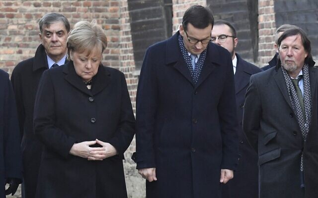 La chancelière allemande Angela Merkel et le premier ministre polonais Mateusz observent une minute de silence devant le Mur des noms, à Auschwitz, le 6 décembre 2019. (Crédit : John MACDOUGALL / AFP)