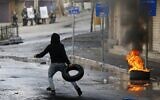 Un manifestant palestinien lance un pneu lors d'affrontements avec les forces de sécurité israéliennes dans la ville de Hébron, au sud de la Cisjordanie, le 9 décembre 2019, au milieu d'une grève générale contre les activités de construction israéliennes. (HAZEM BADER / AFP)