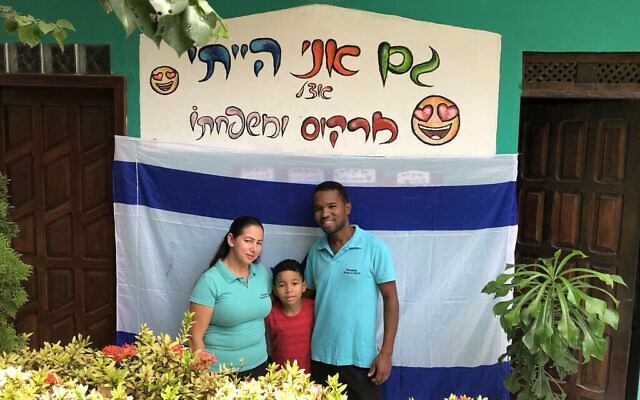 La famille Santos pose à l'endroit où l'on peut lire sur la photo : "J'étais aussi avec Marcos et sa famille", à l'hôtel Sampa no Morro. (Marcus Gilban/JTA)