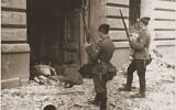 Des gardes Askari ou Trawniki regardent par une porte les corps des Juifs tués pendant la répression du soulèvement dans le ghetto de Varsovie. (Crédit : musée de la Shoah de Washington)
