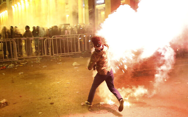Un manifestant anti-gouvernemental lance des fusées contre la police anti-émeute, en arrière-plan, lors d'une manifestation près de la place du Parlement, au centre de Beyrouth, Liban, le 15 décembre 2019. (Crédit : AP Photo/Hussein Malla) Un manifestant anti-gouvernemental lance des fusées contre la police anti-émeute, en arrière-plan, lors d'une manifestation près de la place du Parlement, au centre de Beyrouth, Liban, le 15 décembre 2019. (Crédit : AP Photo/Hussein Malla)