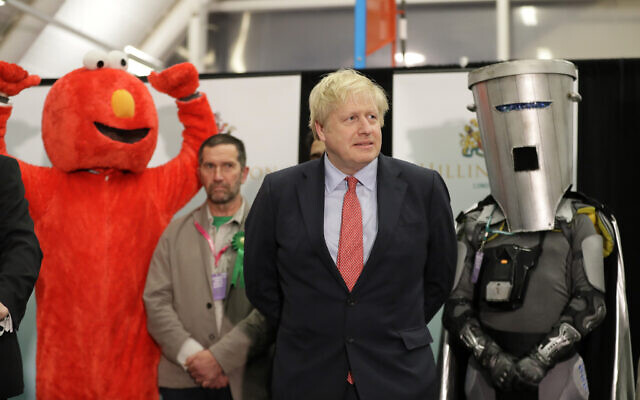 Bobby Smith, militant politique et militant des droits des pères et fondateur et chef du parti "Give Me Back Elmo", à gauche, et le candidat indépendant Count Binface se tiennent de chaque côté du Premier ministre britannique et chef du Parti conservateur Boris Johnson et attendre la déclaration du décompte électoral Uxbridge et South Ruislip à Brunel University, Londres, le 13 décembre 2019. (Crédit ; AP/Kirsty Wigglesworth)