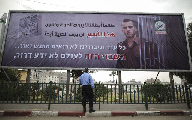 Un policier du Hamas regarde un panneau d'affichage dans la ville de Gaza de l'aile militaire du groupe terroriste représentant le portrait du soldat israélien Oron Shaul, qui a été tué dans la guerre de Gaza en 2014, le 29 décembre 2017. (Crédit : Wissam Nassar/Flash90) Un policier du Hamas regarde un panneau d'affichage dans la ville de Gaza de l'aile militaire du groupe terroriste représentant le portrait du soldat israélien Oron Shaul, qui a été tué dans la guerre de Gaza en 2014, le 29 décembre 2017. (Crédit : Wissam Nassar/Flash90)